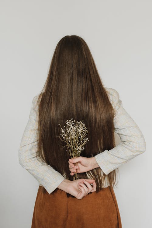 Free Backview of Woman with Long Hair holding Flowers  Stock Photo