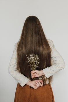 一位长发女子手持小花，背影平静安详