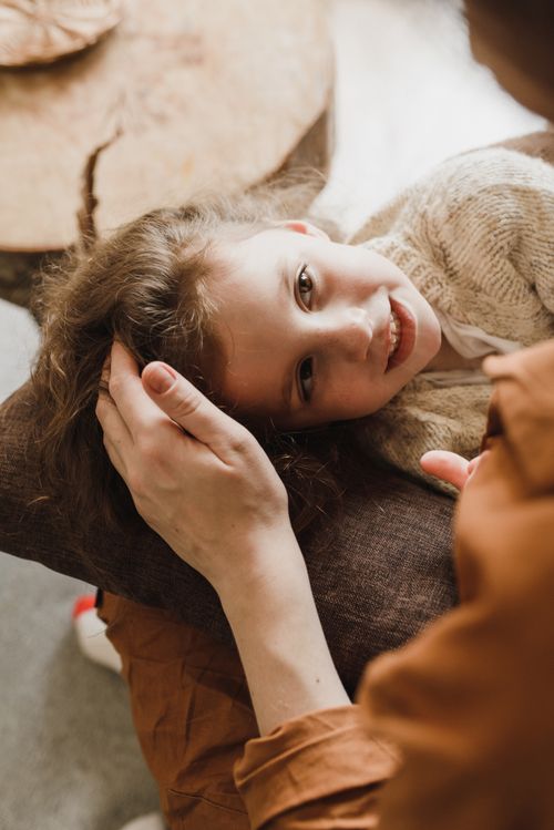 Free A child lies on a pillow, comforted by a parent's touch. Warm and intimate indoor setting. Stock Photo
