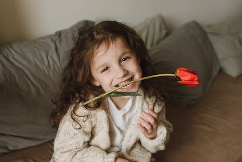 Free Girl Biting the Stem of a Red Flower Stock Photo
