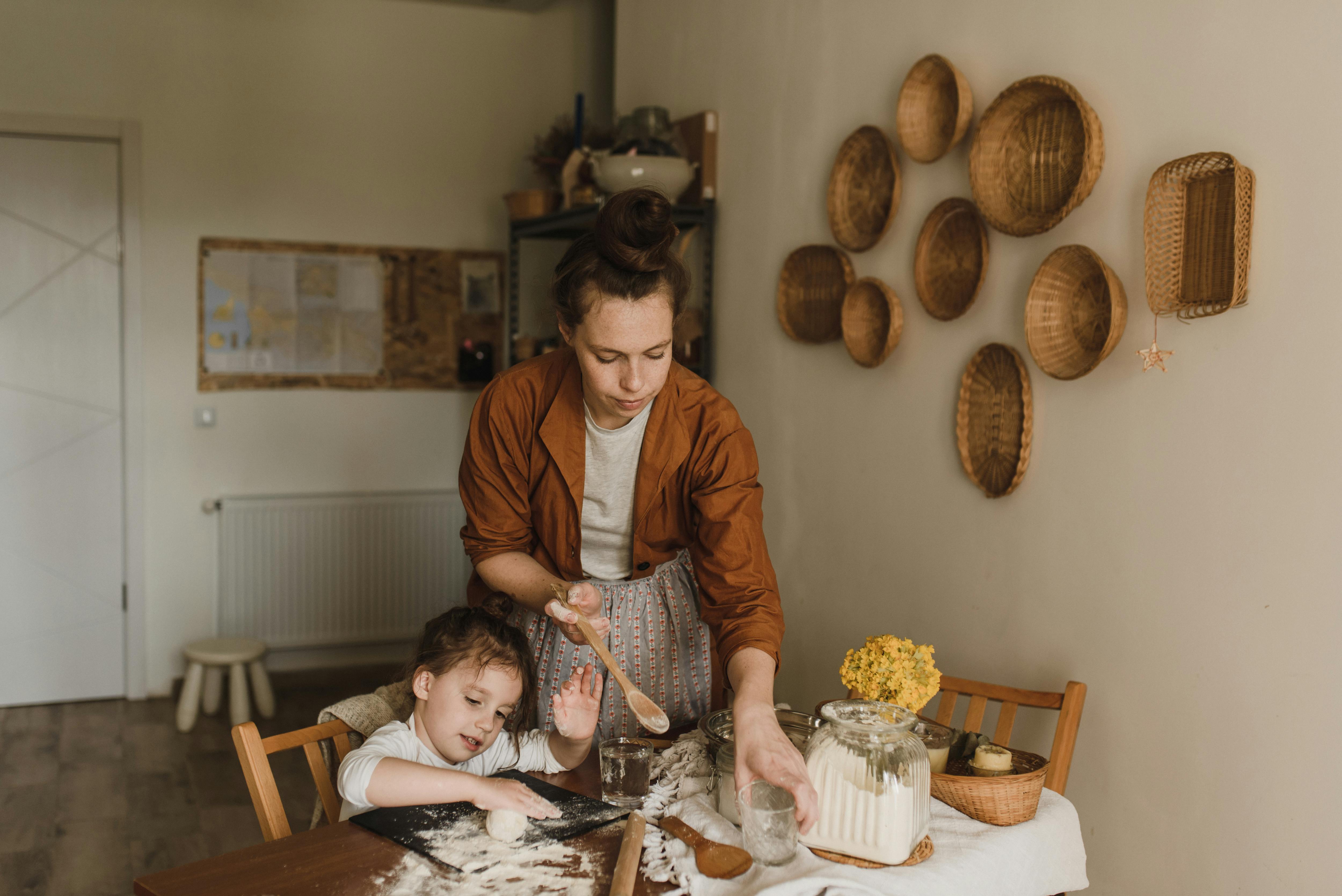 girl kneading dough beside a woman