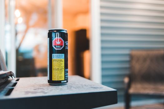 Colorful can of cannabis drink with text and image on shiny surface in building