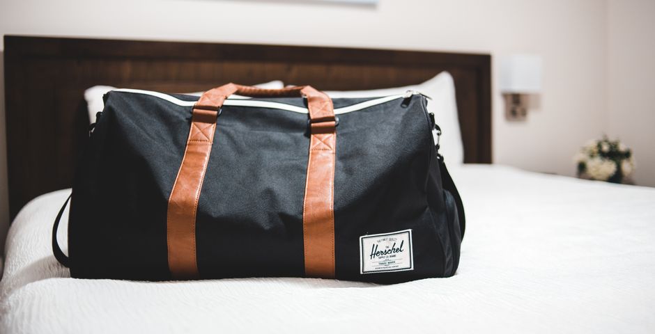 A suitcase on a hotel bed — bed bugs hitchhike home in luggage from travel and short stays