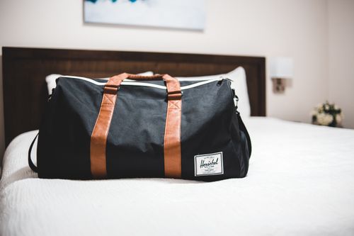 Free Contemporary baggage bag with inscription on white bed cover in light hotel room Stock Photo