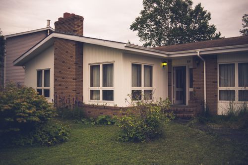Free Contemporary residential house facade near grass meadow with bushes under cloudy sky in twilight Stock Photo