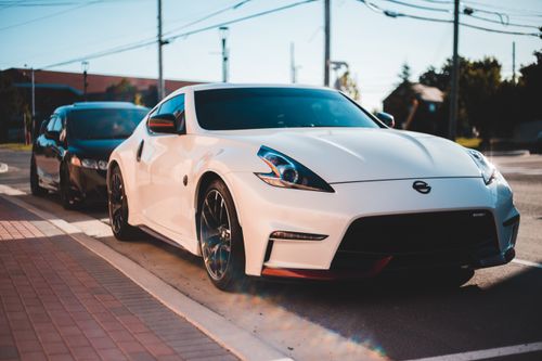Free White tuned sports cars parked on asphalt road under wires and blue cloudless sky in settlement on blurred background Stock Photo