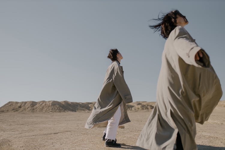 Women Wearing Trench Coats Standing On Dirt Ground