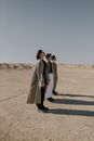 Group of People Wearing Trench Coats Standing on Sand Dunes
