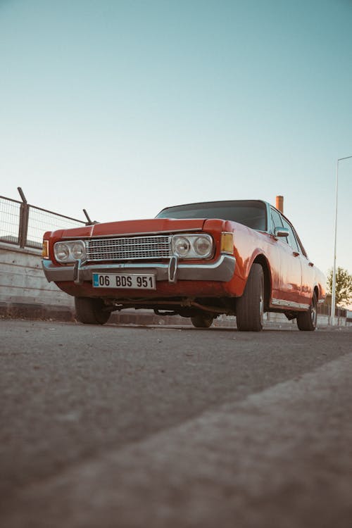 A Red Vintage Car Parked on Asphalt Road