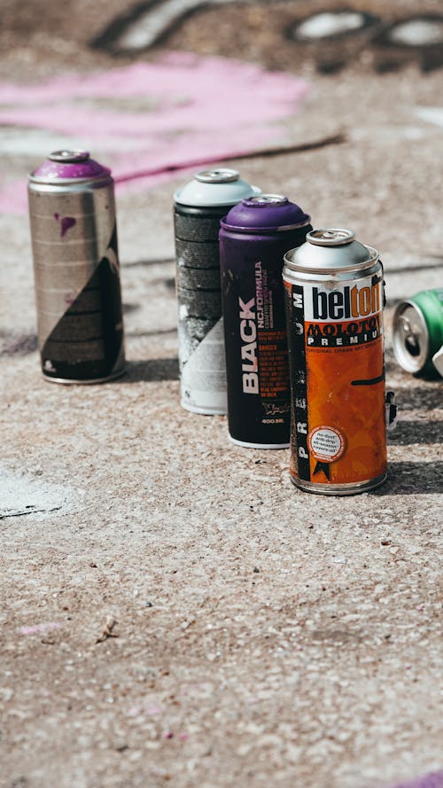 Cans with spray paint placed on concrete pavement on street
