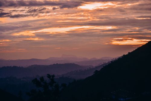 Free A dramatic mountain landscape at sunset with moody sky and misty hills. Stock Photo