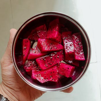 Vibrant sliced dragon fruit in a hand-held bowl, showcasing its fresh, nutritious appeal.