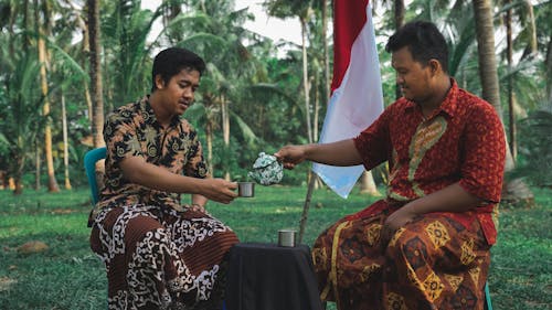 Two Men in Traditional Clothing Pouring Tea