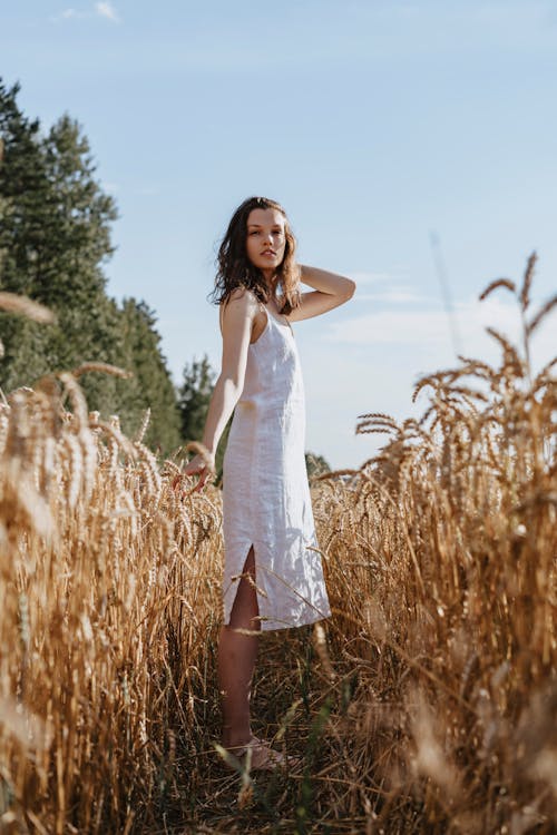 Woman in White Sleeveless Dress Standing on Brown Grass Field