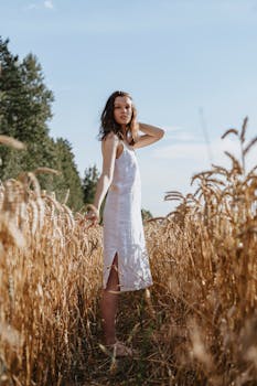 蔚蓝的天空下，一位身穿白裙的女子静静站在金色麦田中间