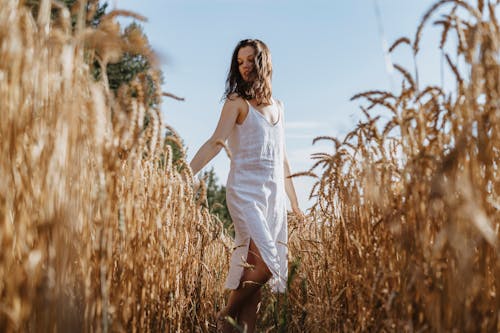Woman in White Dress Standing on Brown Grass Field