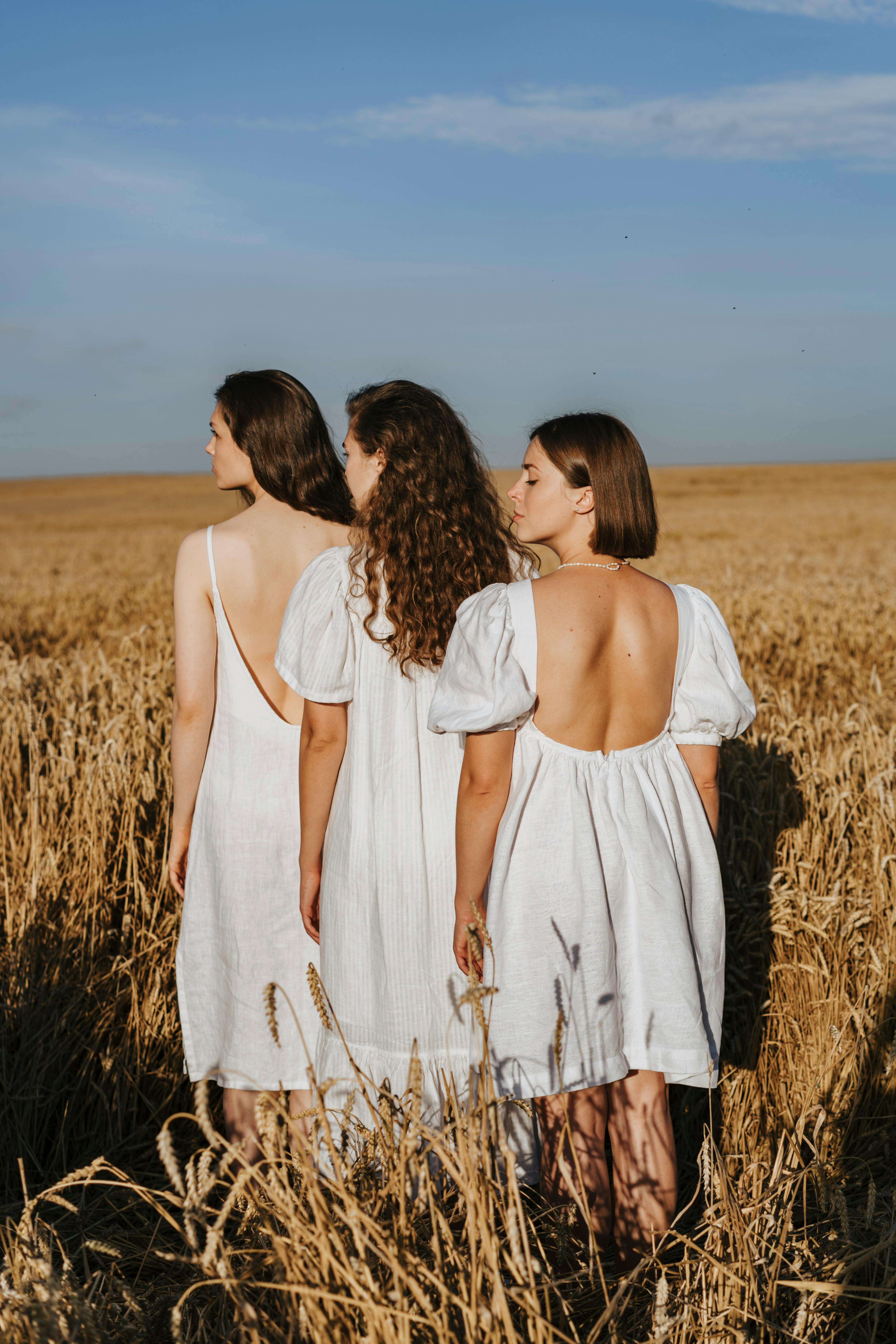 three women standing in crop field under blue sky