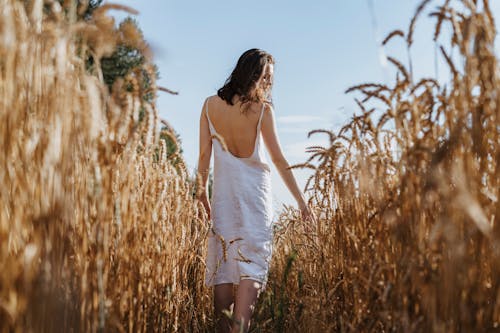 Woman in White Spaghetti Strap Dress Standing on Wheat Field