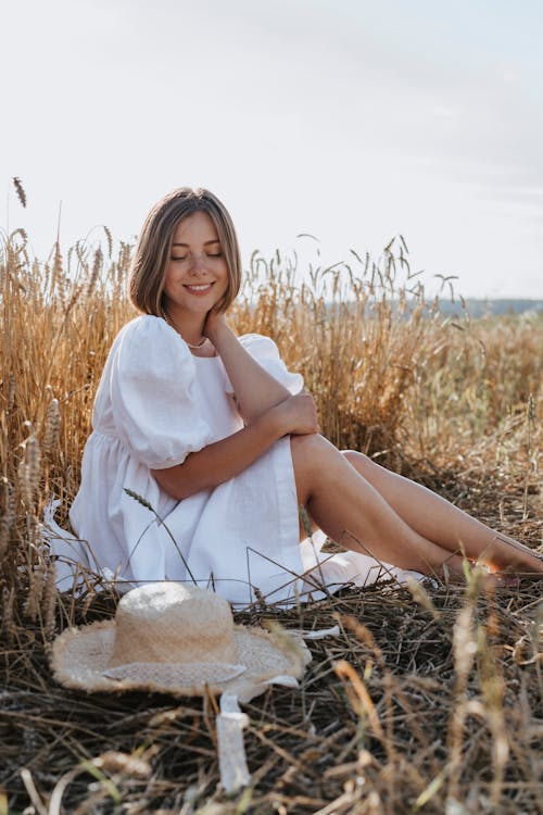 Woman in White Dress Sitting on Brown Grass