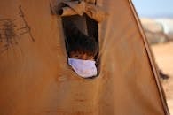 Boy in face mask looking out hole in tent