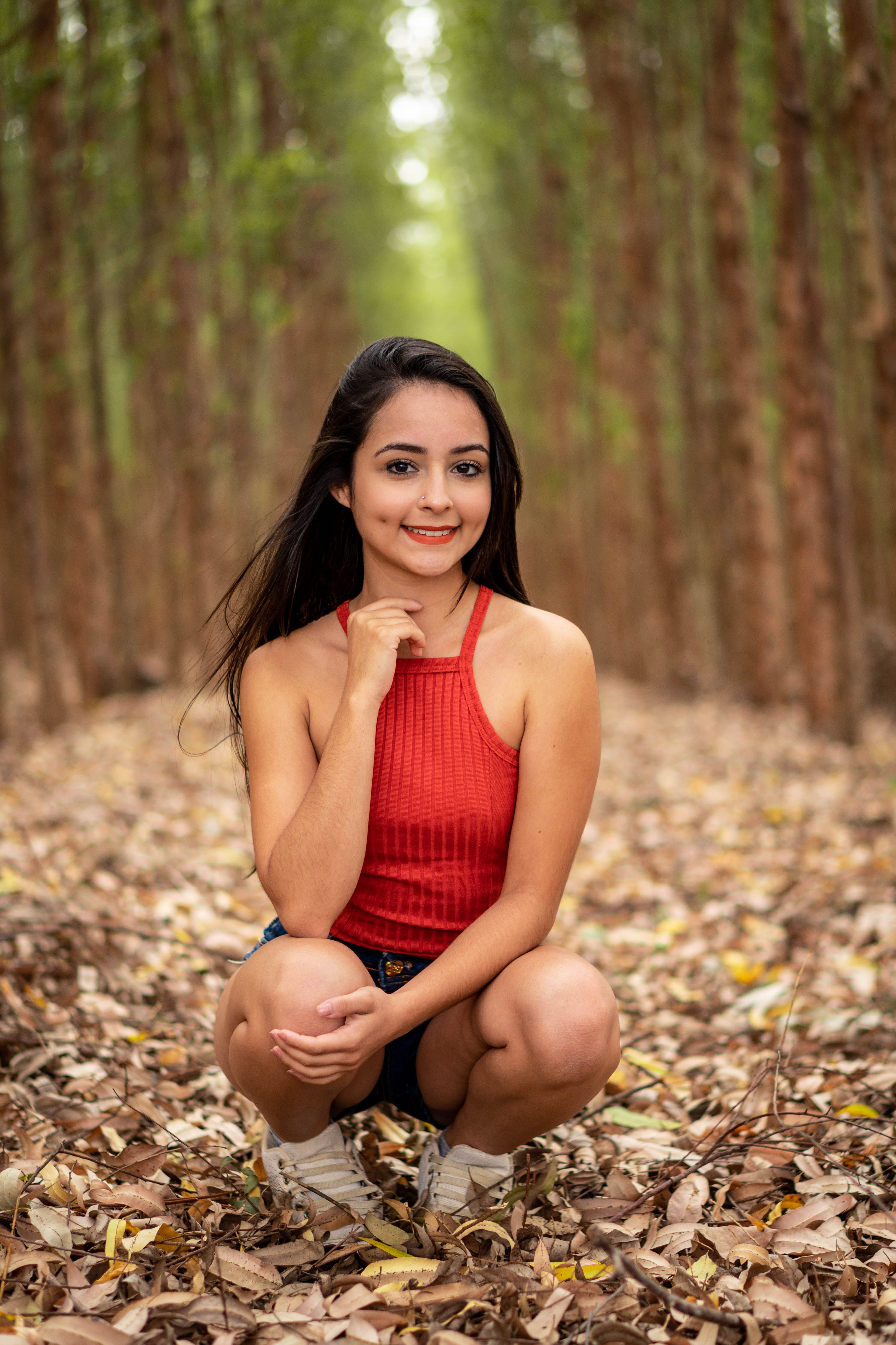 Woman in Red Top Sitting on Brown Dried Leaves · Free Stock Photo