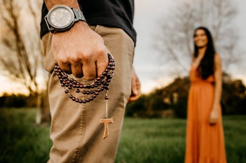 Unrecognizable man with prayer beads standing in park near woman