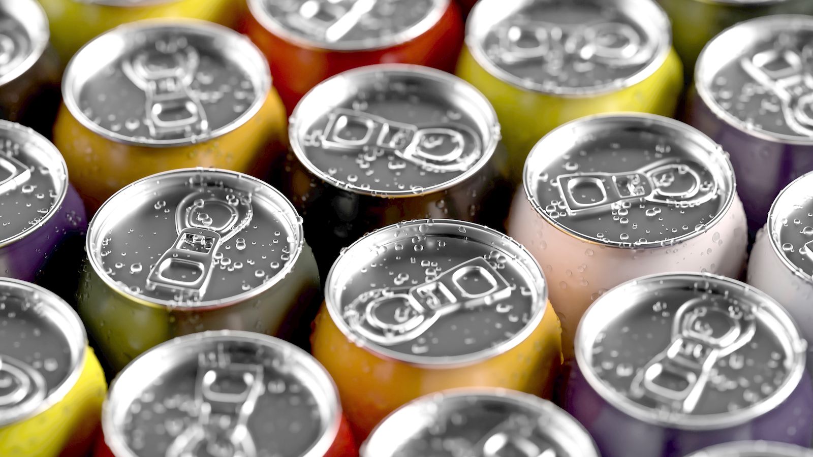Close-up of colorful beverage cans with condensation droplets on the pull tabs.