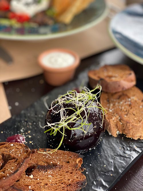 Close-up of a Lunch Meal with Dark Bread on a Black Plate 