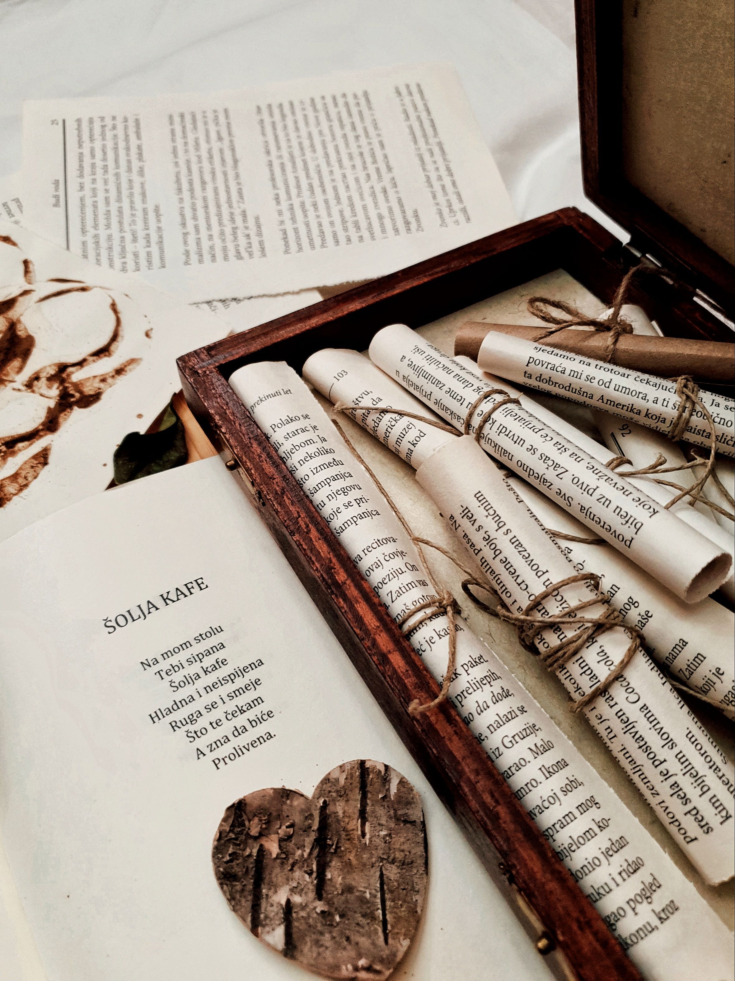 Artistic still life of books and scrolls in a wooden box with rustic heart decor.