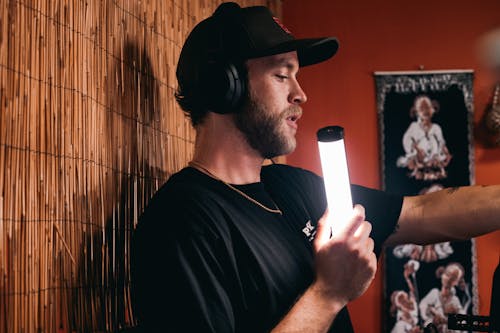 Man Wearing Cap and Headset Holding a Light 