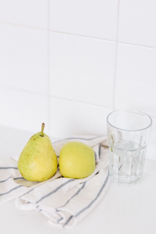 Free A pear and apple with a glass of water on a striped cloth, perfect for diet and nutrition themes. Stock Photo