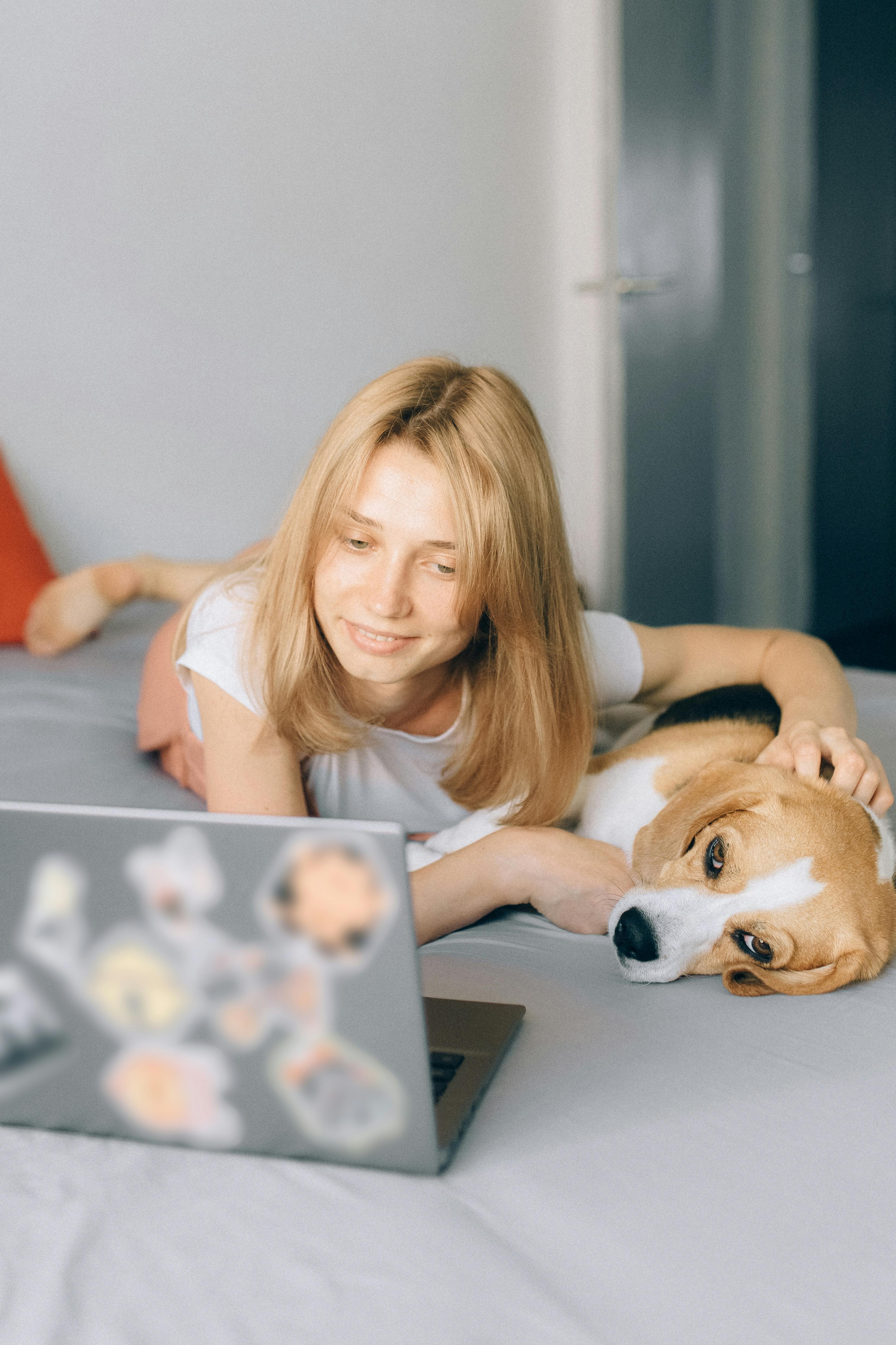 woman petting her dog and looking at her laptop