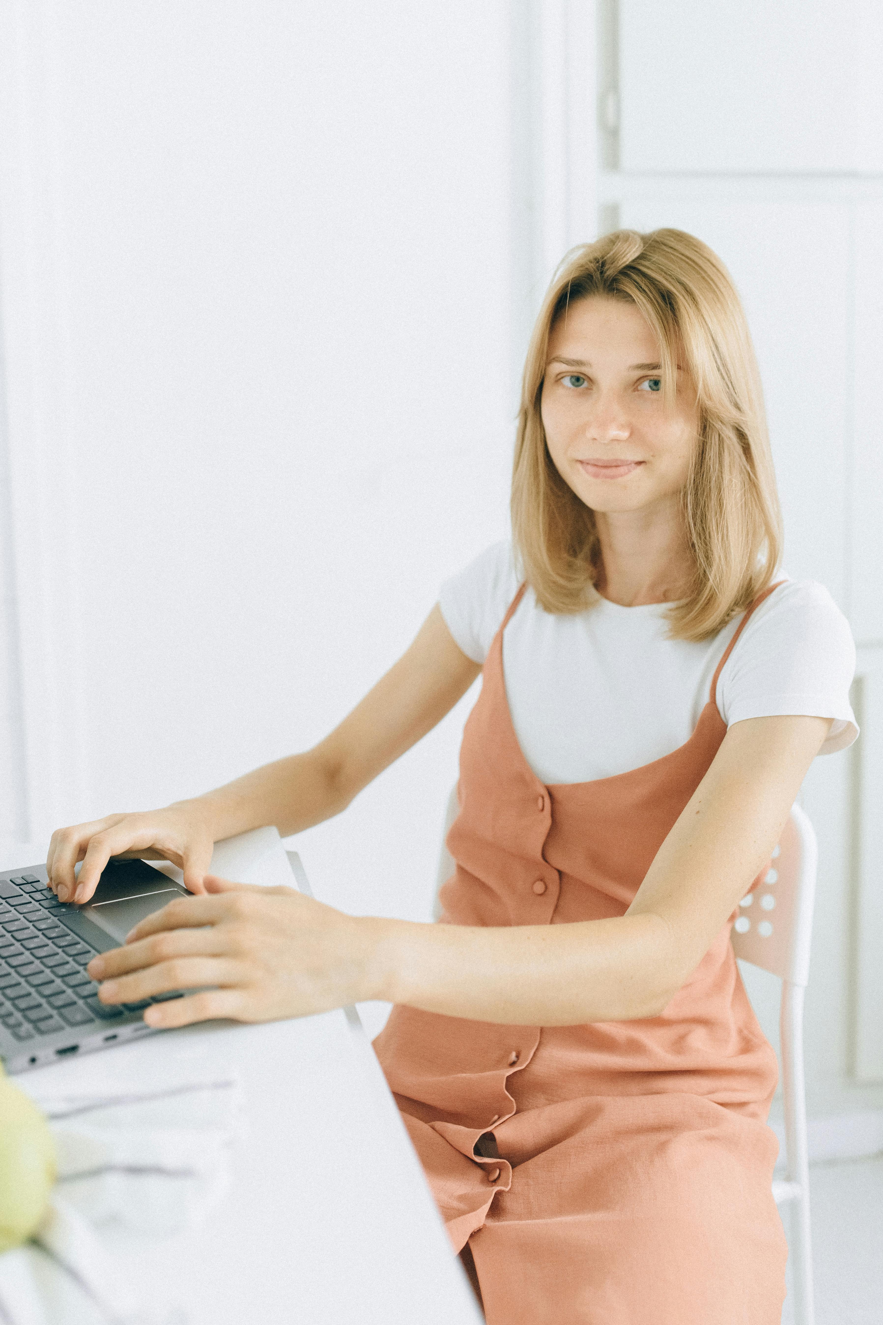 a woman sitting on a chair while using her laptop