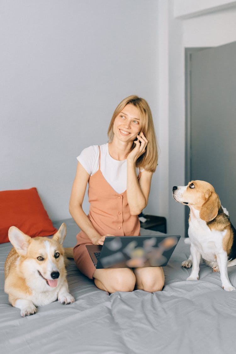 A Woman Talking On The Phone With Her Dogs In The Bed