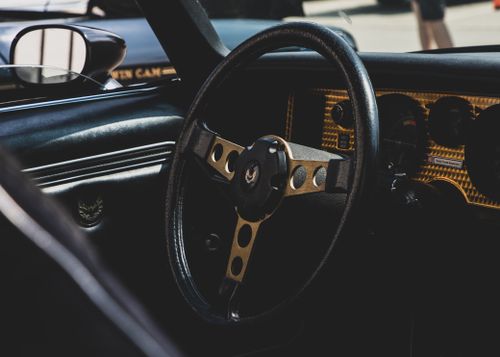 Free Close-up of a vintage car steering wheel with rich textures and detailed dashboard design. Stock Photo