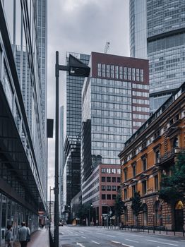 Empty asphalt road located among buildings with glass mirrored windows located in modern city district