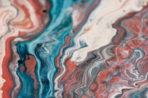 Creative abstract background with vivid multicolored paints mixed together in technique of fluid art