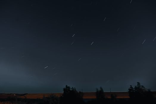 乡村的田野上方，夜空中星星在黑暗中长时间闪亮