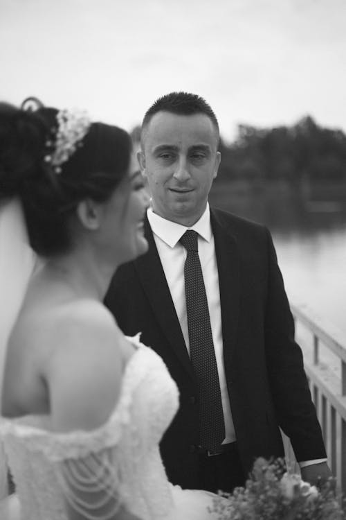 Groom standing near happy bride on waterfront