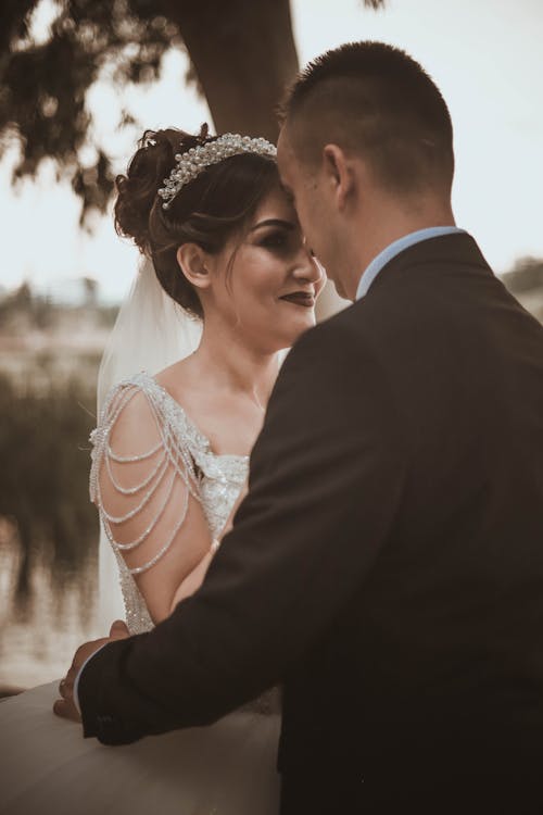 Side view of happy just married lovers hugging gently while standing close to each other during romantic wedding day