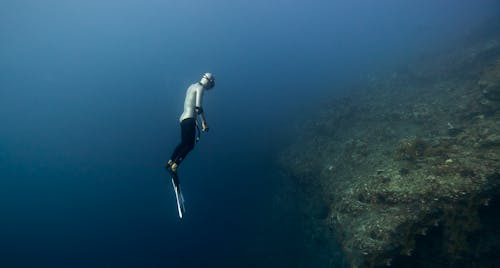 Diver Swimming Over Drop in Sea Floor