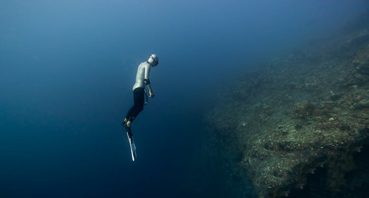 Diver Swimming Over Drop In Sea Floor