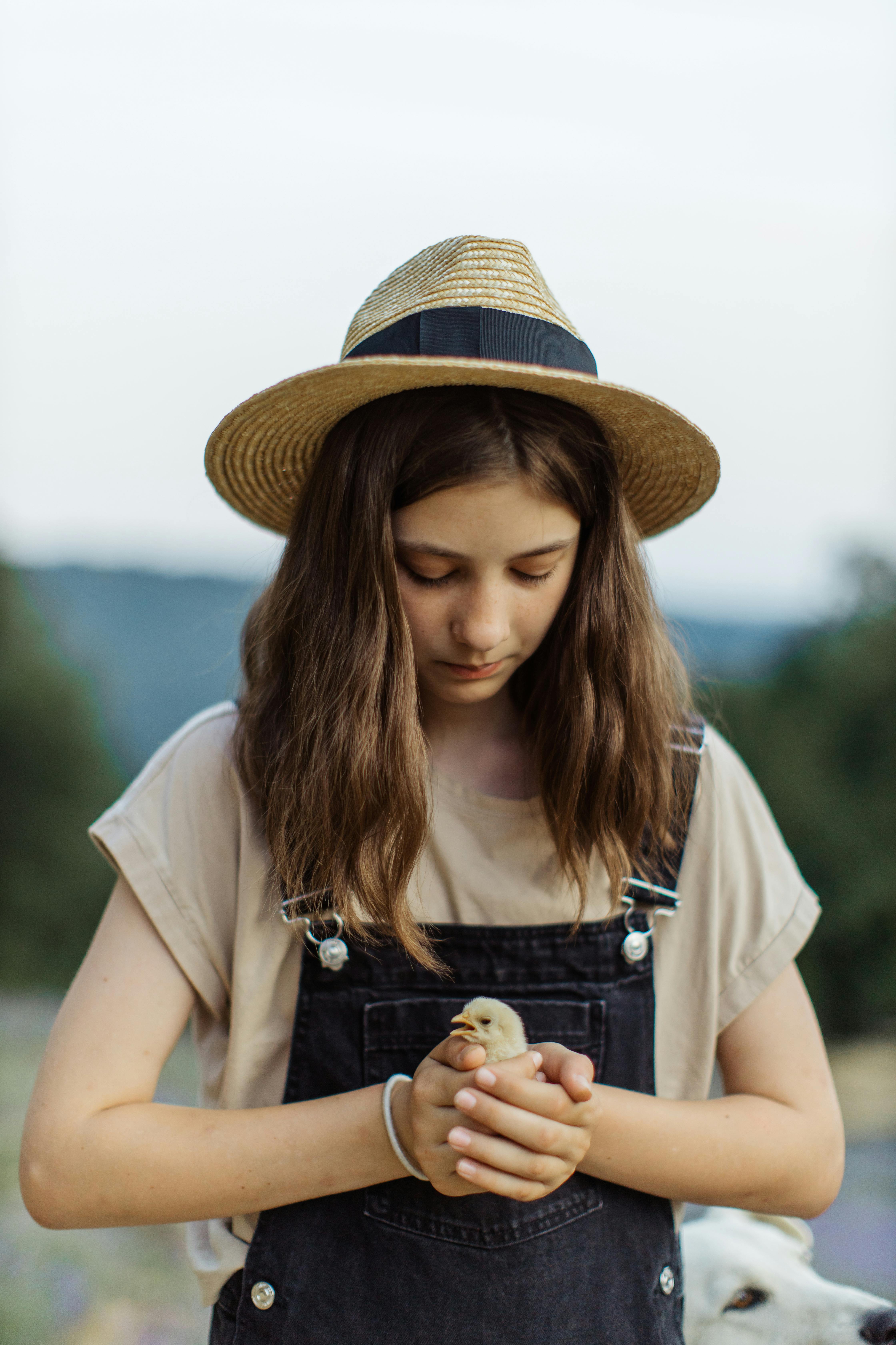 close up shot of a girl with sun hat holding a chick