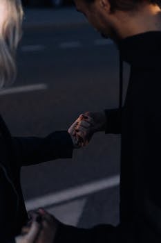 在昏暗的光线下，一对夫妇温柔地牵着手，象征着爱与联系