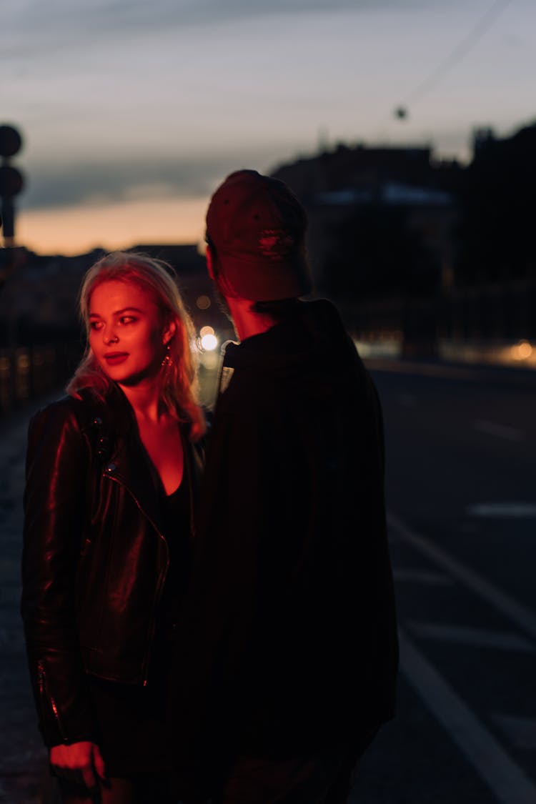 A Couple Standing On The Street At Night