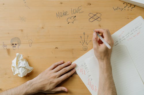 Man Writing on Wooden Desk in Classroom