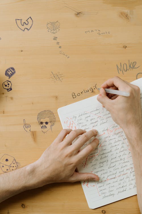 Free Person Writing on Wooden Surface Stock Photo