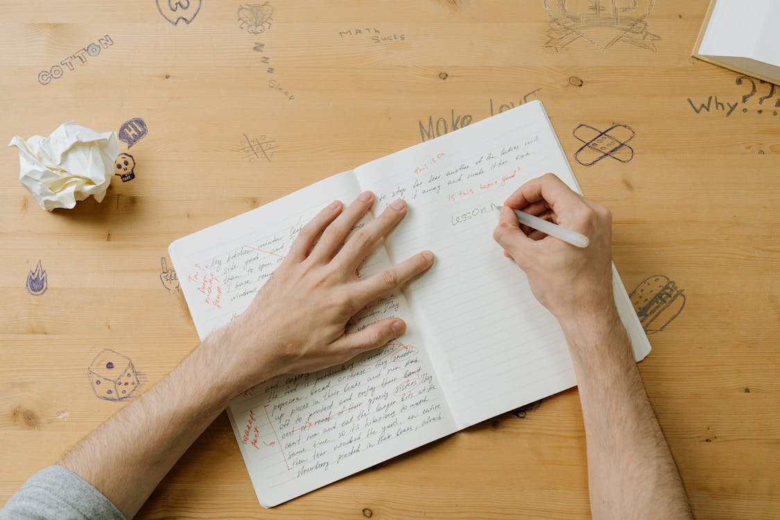 Man Writing in Notebook in a Classroom