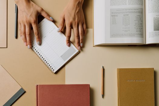 Hands arranging books and planners on a desk