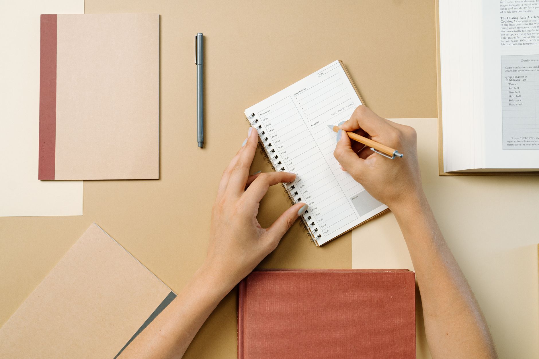 A hand writing on a neat paper planner on a clear desk